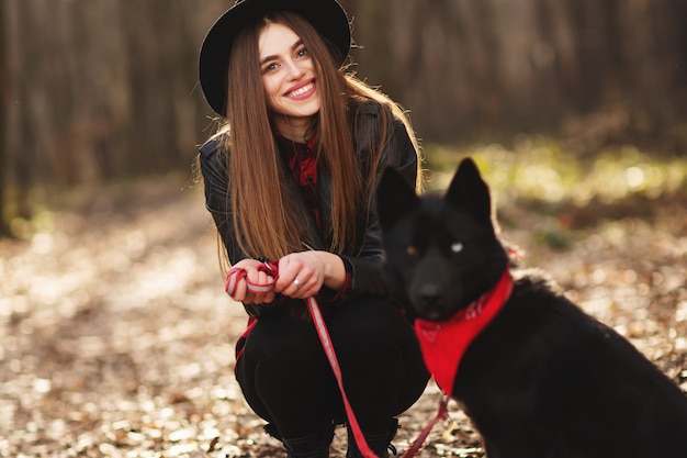 Moça com um cão andando no parque do outono