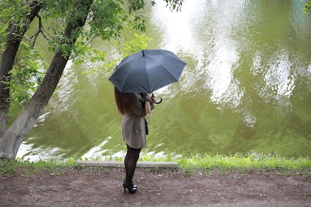 Moça com um casaco em um parque de primavera no rainxa