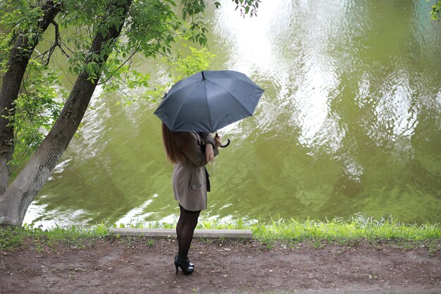 Moça com um casaco em um parque de primavera no rainxa