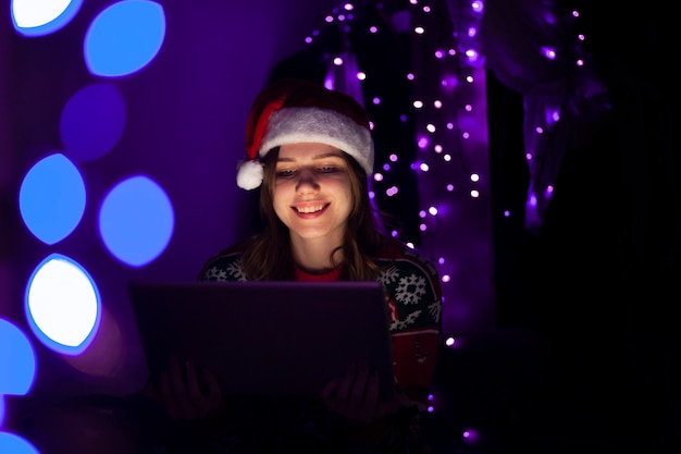 Moça com um laptop no chapéu de Papai Noel