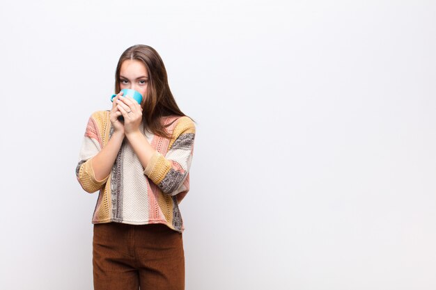 Moça com uma xícara de café contra a parede branca