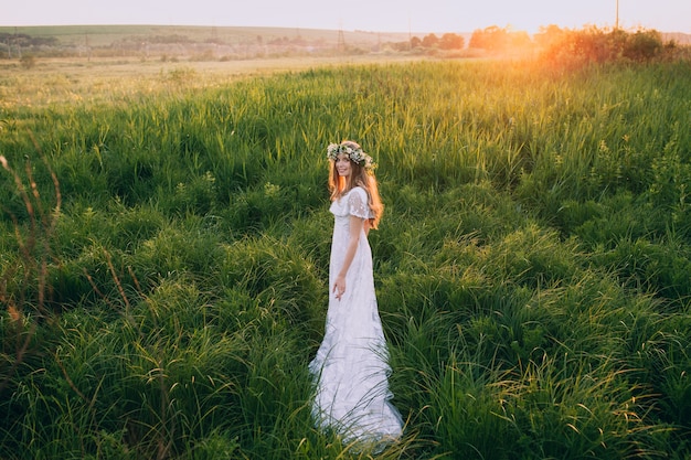 Moça em um vestido branco no prado. Mulher em um lindo vestido longo posando em um prado
