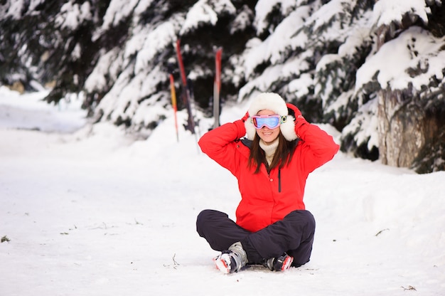 Moça em uma jaqueta esportiva vermelha no esqui na floresta de inverno,