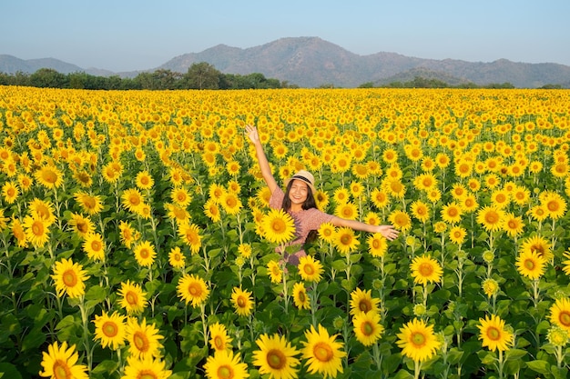 Moça feliz no campo do girassol com céu azul