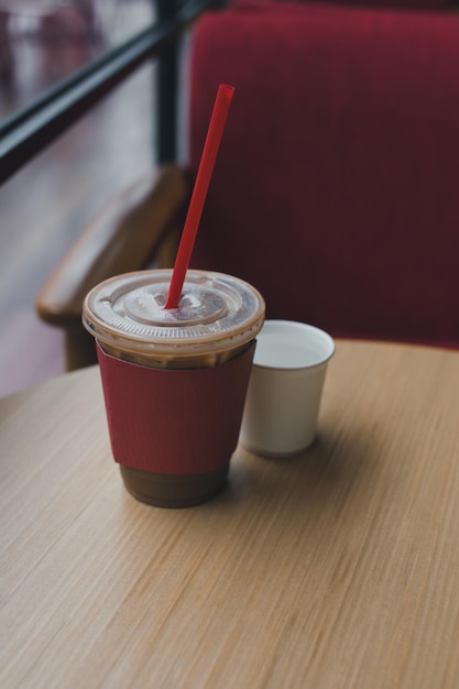 Moca helada con hielo en una taza de plástico cubierta con una funda de papel rojo en una mesa en un cierto café