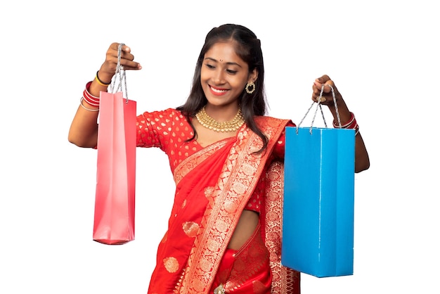 Moça indiana bonita que prende e que levanta com sacos de compras em um fundo branco