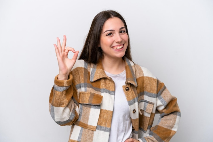 Foto moça isolada no fundo branco, mostrando sinal de ok com os dedos