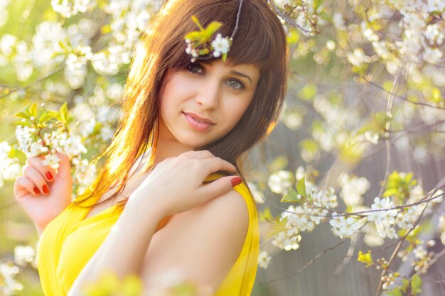 Moça no vestido amarelo na primavera na flor de cerejeira