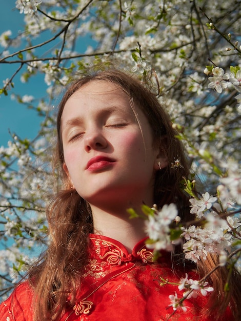 Moça no vestido vermelho das flores da primavera