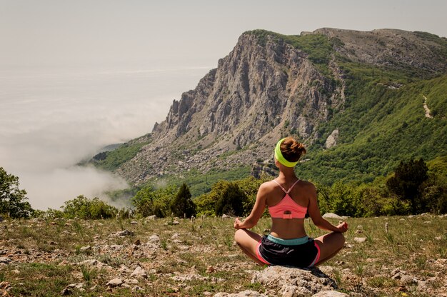 Moça que faz o exercício da aptidão da ioga ao ar livre na paisagem das montanhas.