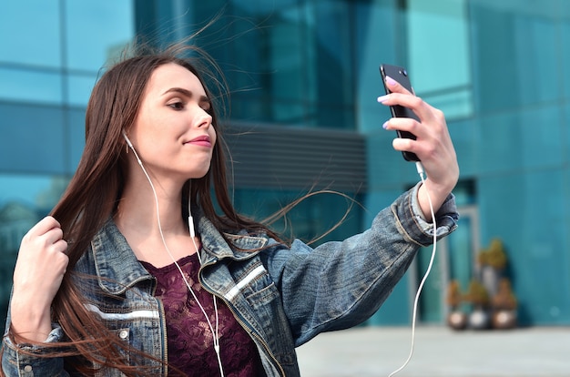 Moça que faz o selfie no fundo de um prédio de escritórios