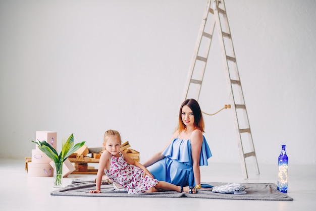 Moça se divertindo com a mãe na sala decorada branca. mãe adorável com a filha dela.