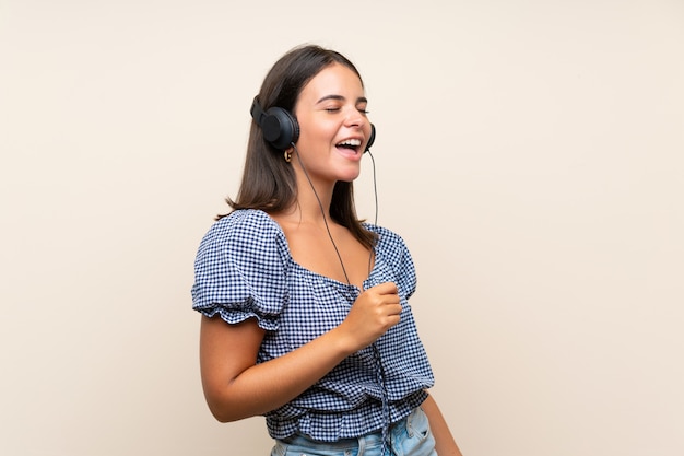 Moça sobre parede isolada, ouvindo música com fones de ouvido