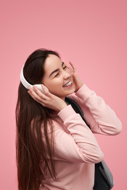 Moça sorridente curtindo música com os olhos fechados em fones de ouvido
