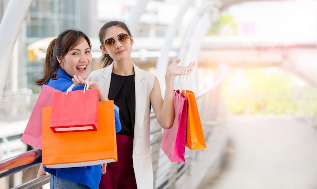 Moças bonitas com sacolas coloridas ao longo do caminho para o shopping