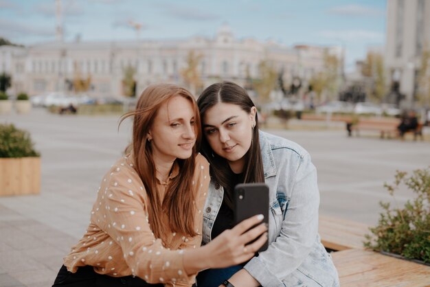 moças sentadas em um parque da cidade com um telefone