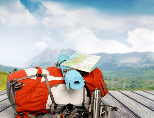 Mochila com mapa e garrafa térmica isolada no fundo. Turismo e temas de viagens.