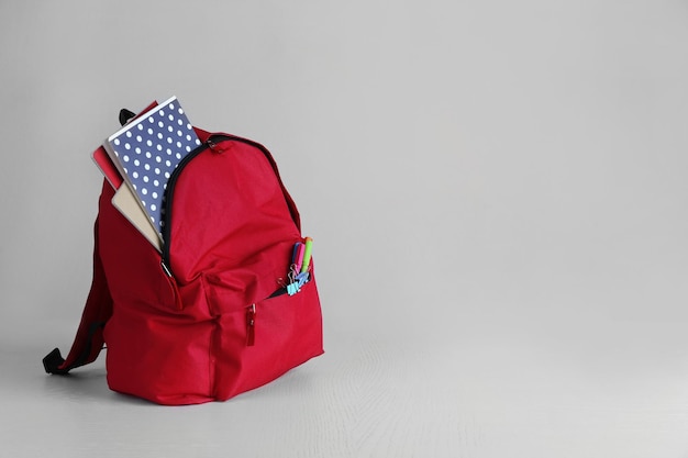 Mochila com suprimentos escolares em mesa de madeira