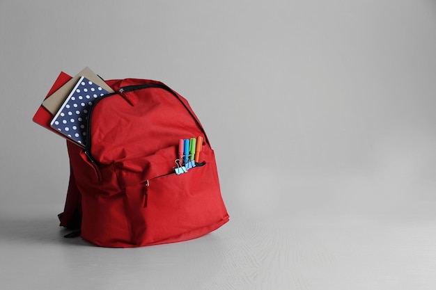 Mochila com suprimentos escolares em mesa de madeira