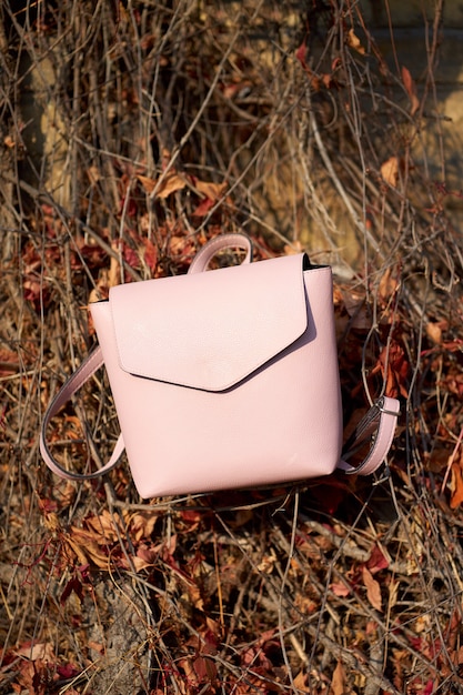 Mochila de cuero rosa con estilo en la pared de otoño.