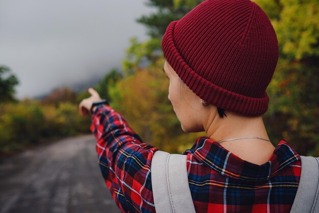 Mochila de menina asiática feliz em fundo de estrada e floresta