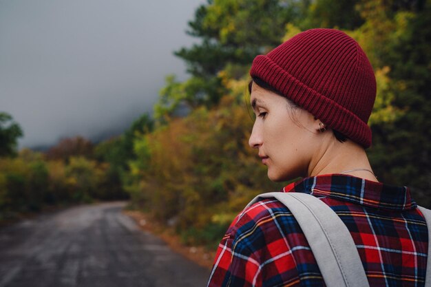 Mochila de menina asiática feliz em fundo de estrada e floresta