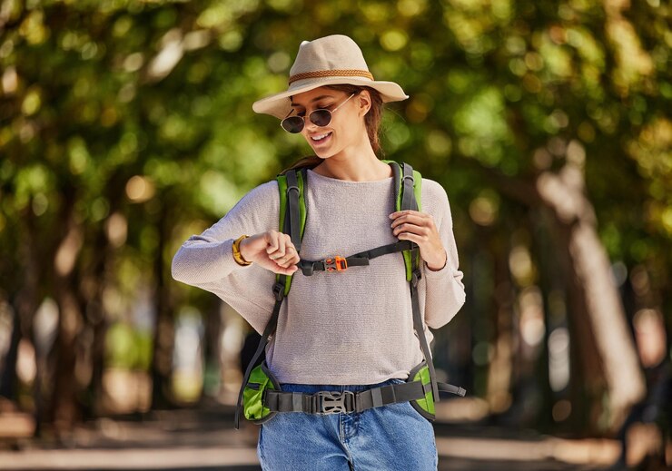 Foto mochila de mulher e verificação do relógio na natureza, viagens turísticas ou aventura em florestas de árvores de parque ou bosques do canadá sorria feliz e turista no relógio de ponto para mapa de localização gps ou tecnologia de caminhada