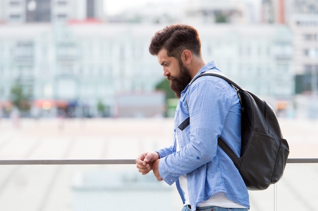 Mochila de turista bonito hipster pensativo. Homem com barba e mochila explorar a cidade. Conceito de viagem. Turista de férias. Fundo urbano do turismo moderno hipster. Procurando por aventuras.