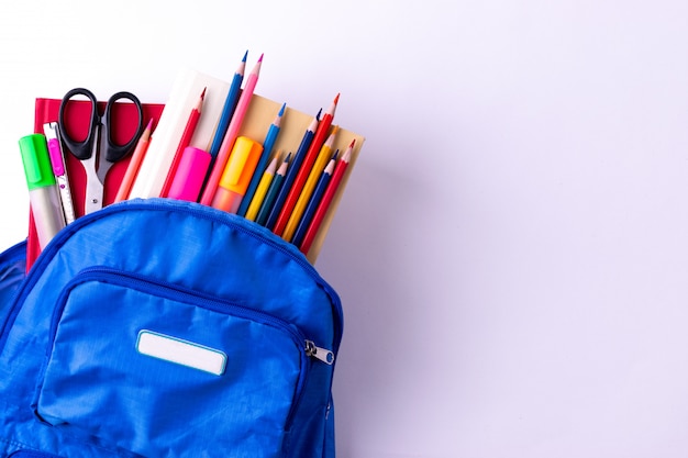 Mochila con diversos efectos de escritorio coloridos en la tabla blanca. Volver al concepto de escuela.