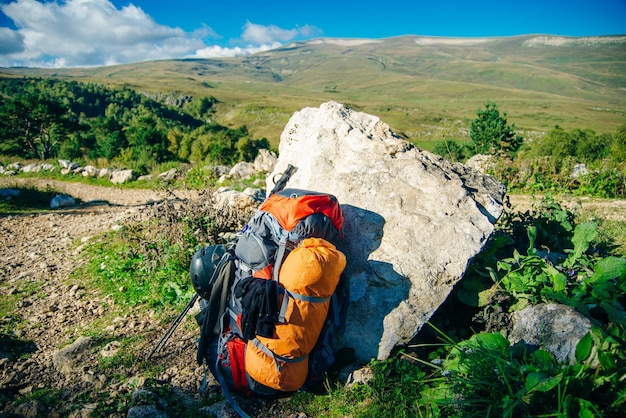 La mochila se encuentra en la parte superior del fondo de las montañas que se extienden hasta el horizonte en un día soleado