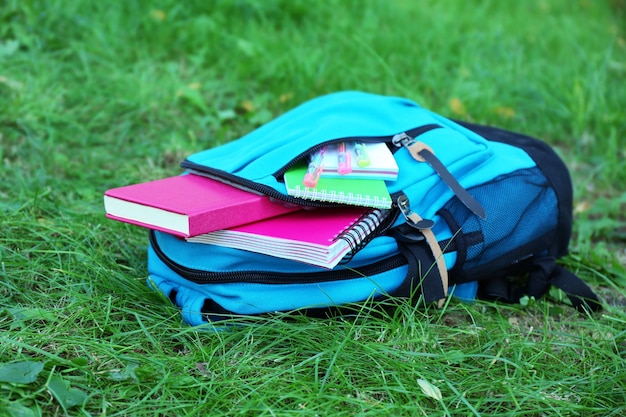 Foto mochila escolar con accesorios en césped verde