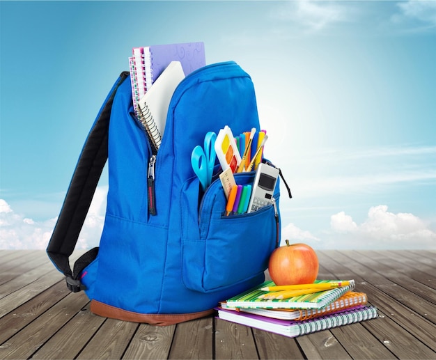 Mochila escolar com artigos de papelaria no fundo