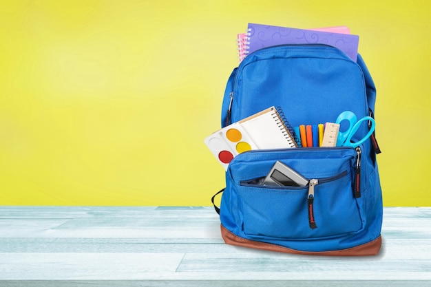 mochila escolar com papelaria escolar em um fundo colorido. Conceito de volta às aulas.