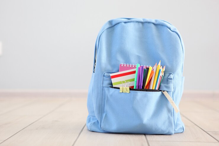 Foto mochila escolar e artigos de papelaria em uma sala iluminada