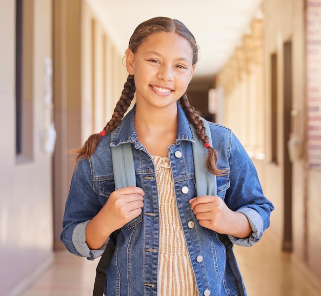 Mochila escolar e retrato de aluna com educação para aprender, estudar e ter conhecimento Sorriso feliz e criança parada no corredor ou corredor com sua bolsa para a aula em um campus de escola secundária