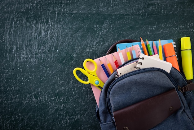 Mochila escolar e suprimentos com lousa. volta ao conceito de escola.