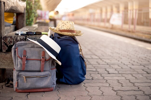 Mochila con gorro, mapa, gafas de sol, auriculares y teléfono inteligente en la estación de tren