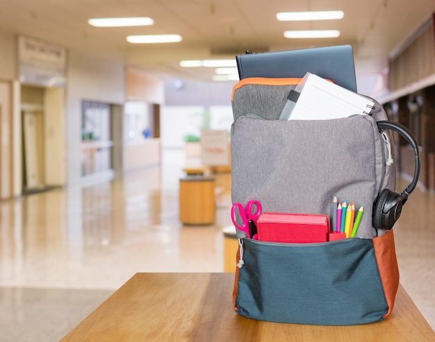 Mochila muy cargada con útiles escolares en el moderno hall de entrada