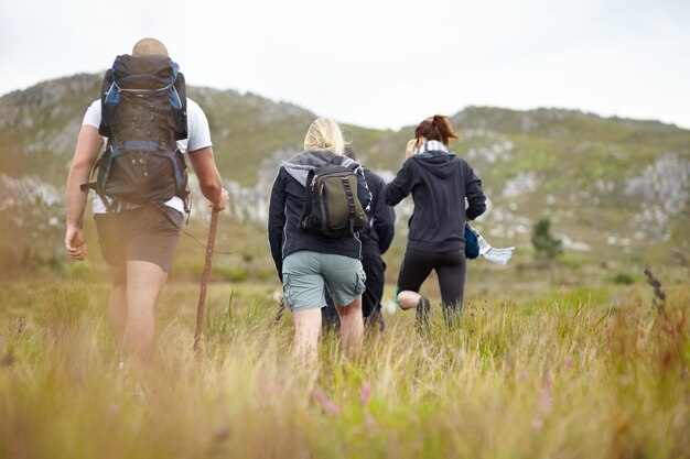 Foto mochila de naturaleza y grupo de amigos en aventura de senderismo en la montaña con libertad de espalda viaje de senderismo y personas caminando en el campo hombres y mujeres en un viaje al aire libre natural juntos