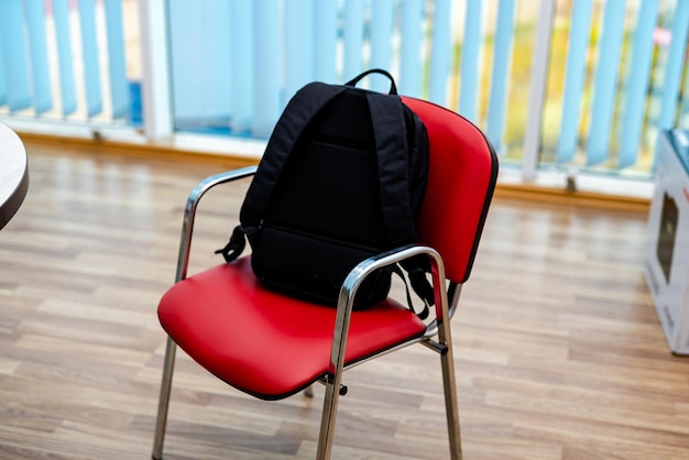 Mochila negra en silla roja Mochila para computadora portátil o libros de estudiantes Regreso a la escuela