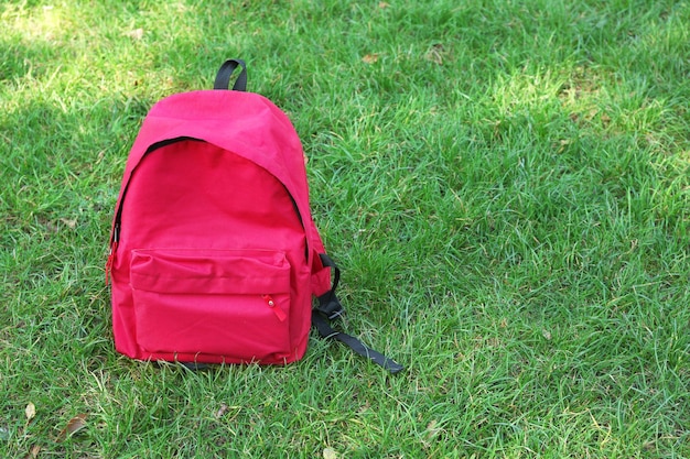 Foto una mochila roja en la hierba verde.