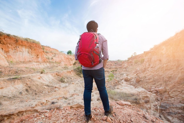 Mochila roja de viaje joven disfrutando de una vista panorámica del abismo de la montaña Viajando a lo largo del concepto de estilo de vida activo