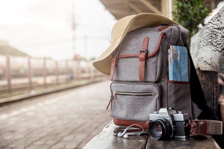 Foto una mochila, un sombrero, un mapa, un teléfono inteligente, un auricular y una cámara en la estación de tren.