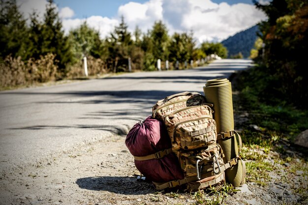 Mochila turística con alfombra cerca de la carretera.