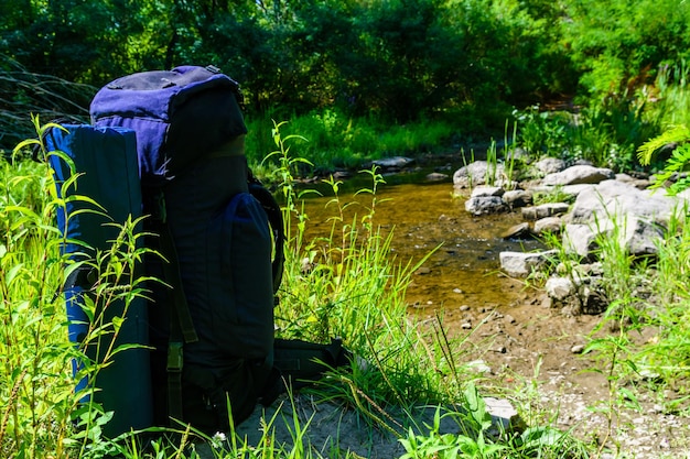 Mochila turística a orillas del río en el bosque