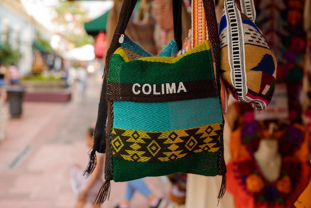Mochilas, bolsas e bolsas feitas com tecidos típicos mexicanos penduradas do lado de fora das lojas de souvenirs