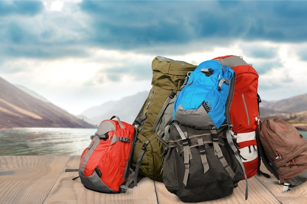 Mochilas de colores en el muelle de madera con lago de montaña en el fondo, concepto de senderismo