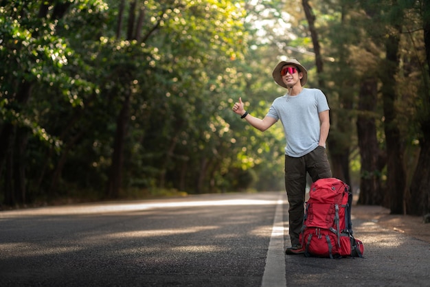 Foto mochileiro asiático feliz caroneiro para transporte de carro para trekking viagem de montanha