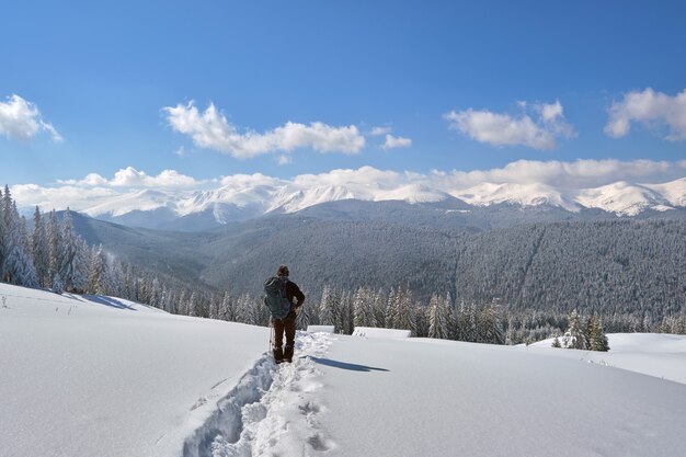 Mochileiro de homem caminhadas encosta da montanha nevada num dia frio de inverno.