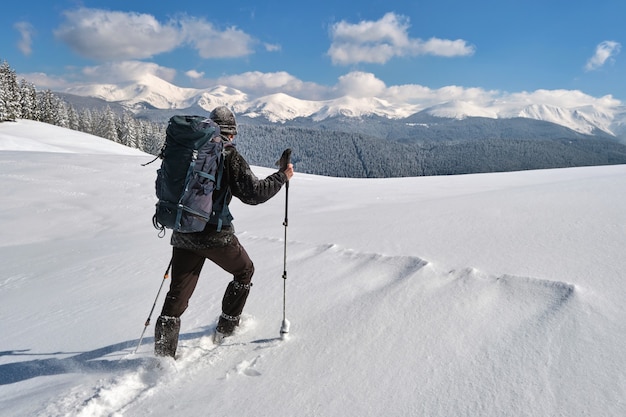 Mochileiro de homem caminhadas encosta da montanha nevada num dia frio de inverno.